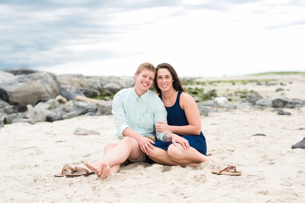 Two brides sitting in the sand on the Jersey Shore of Barnegat Lighthouse