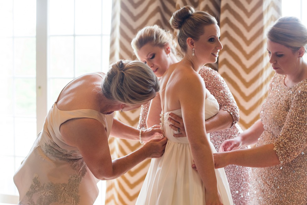 Bride getting into her WTOO by Watters strapless bridal gown with lace coverlet