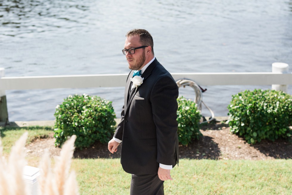 Groom in teal bowtie walking on the waterfront to his Ceremony at Anchor Inn