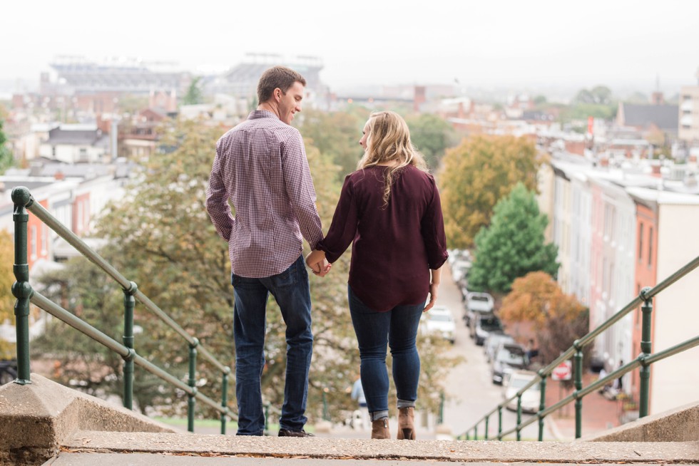 Engaged couple walking down the steps at Federal Hill overlooking Ravens stadium