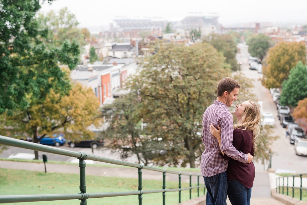 Engaged couple walking down the steps at Federal Hill overlooking Ravens stadium