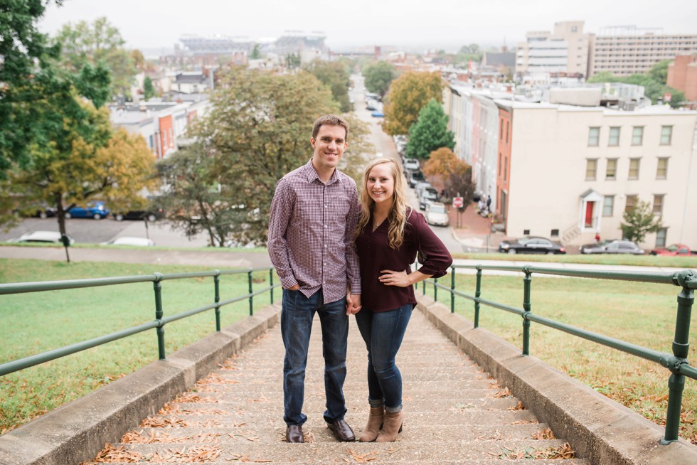 Engaged couple walking down the steps at Federal Hill overlooking Ravens stadium