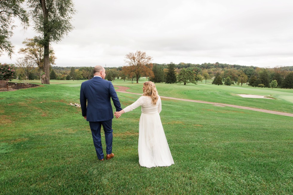 Bride and groom walking on golf course in the fall