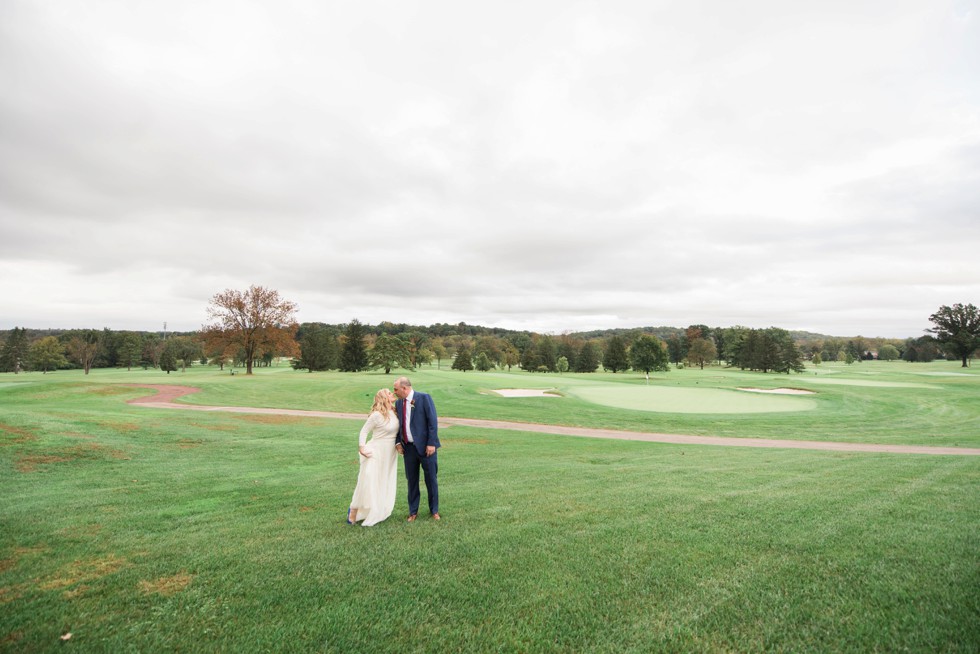 Bride and groom walking on golf course in the fall