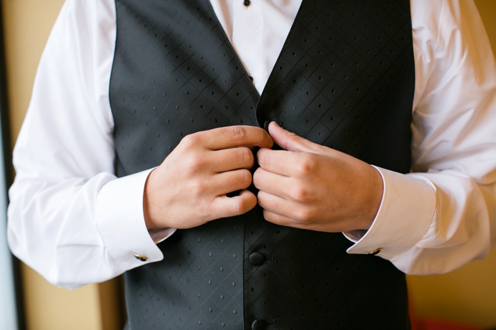 groom getting ready buttoning tux