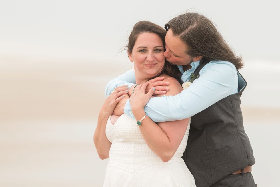 Brides snuggling on the beach