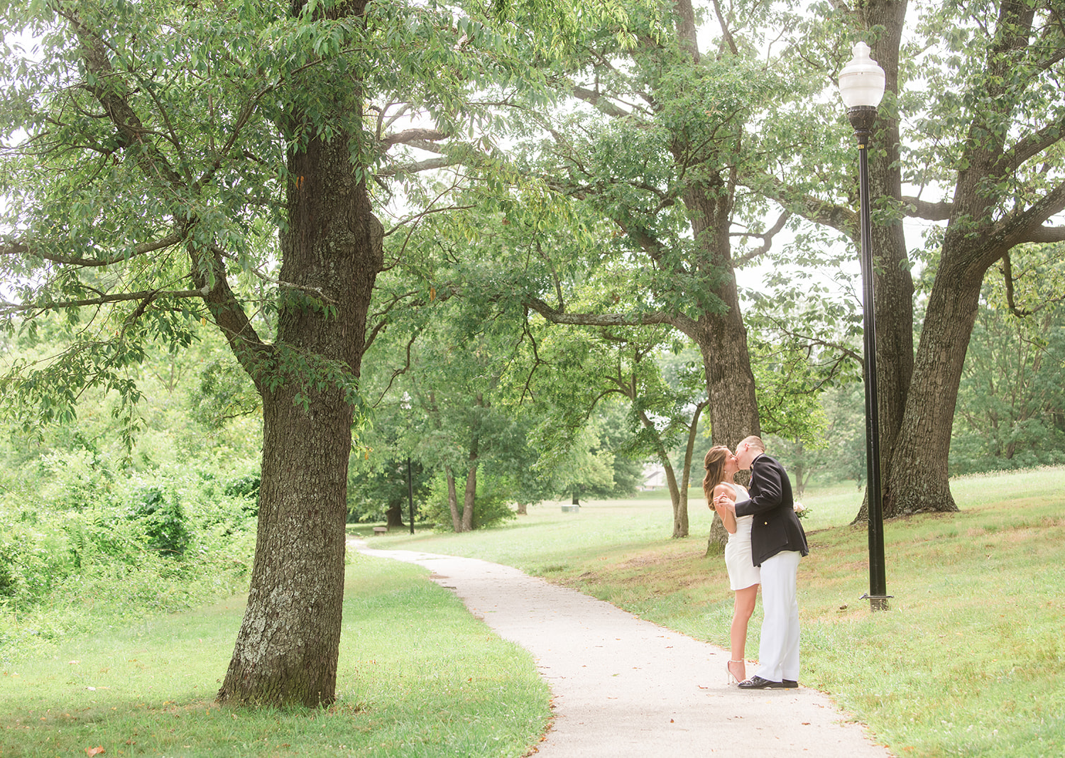 bride and groom share a kiss surrounded by green trees