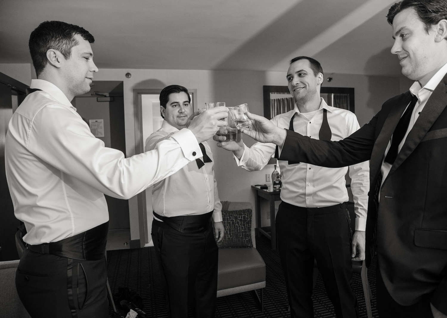 groom and groomsmen sharing a drink and a toast before the wedding