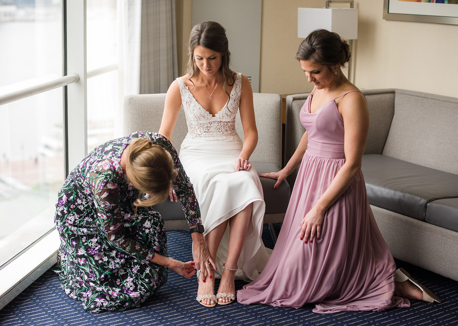 mother of the bride helping the bride put on her wedding shoes