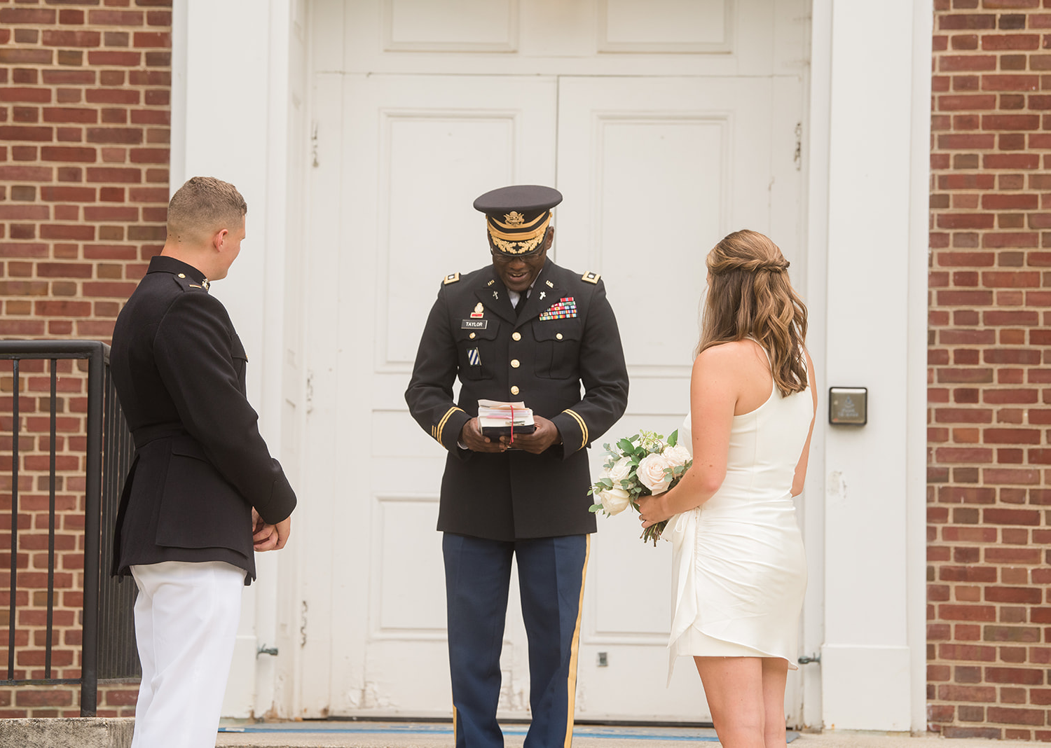 bride and groom standing in front of the chapel listening to the reverend's speech