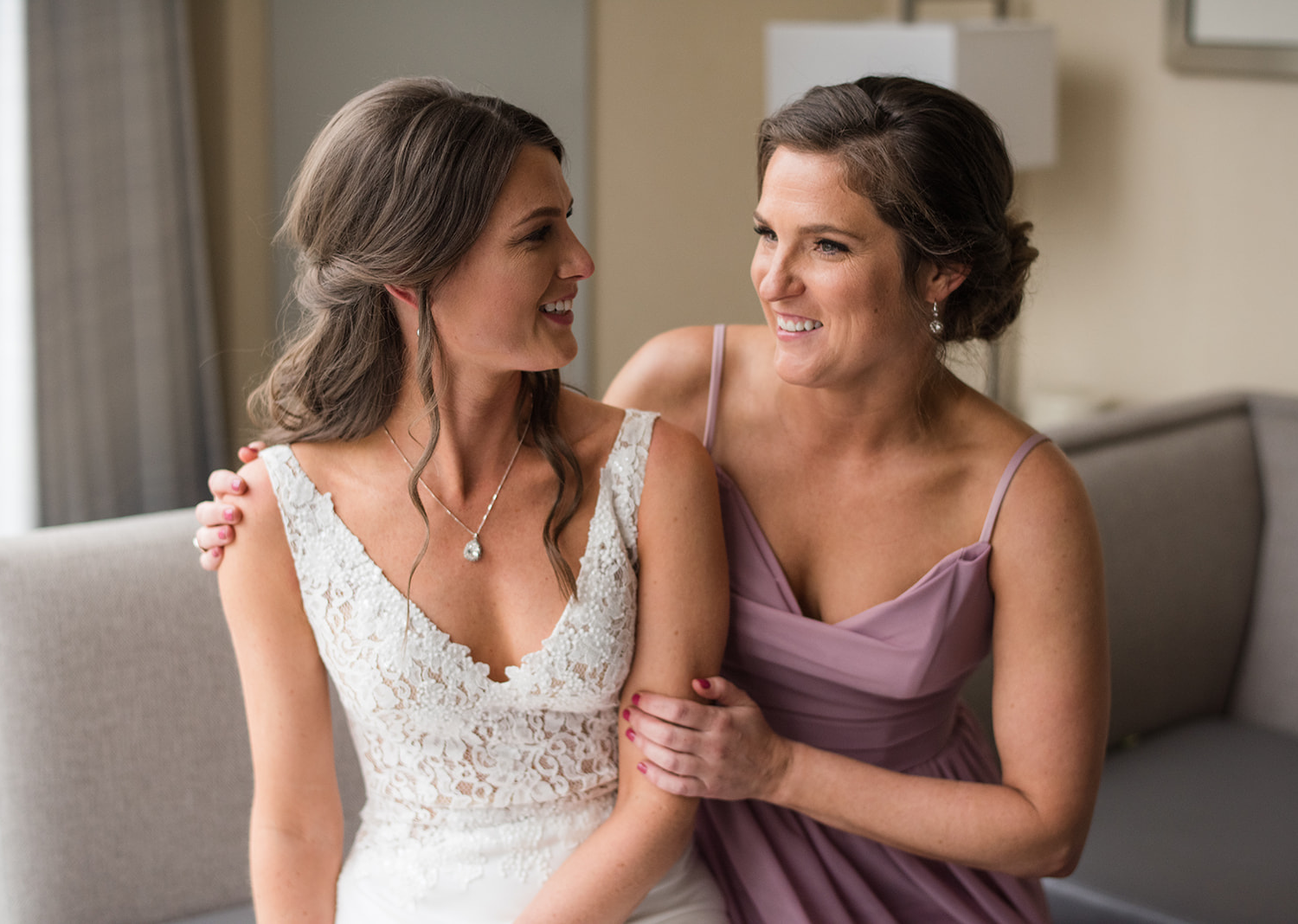 bride and bridesmaid smiling looking at each other