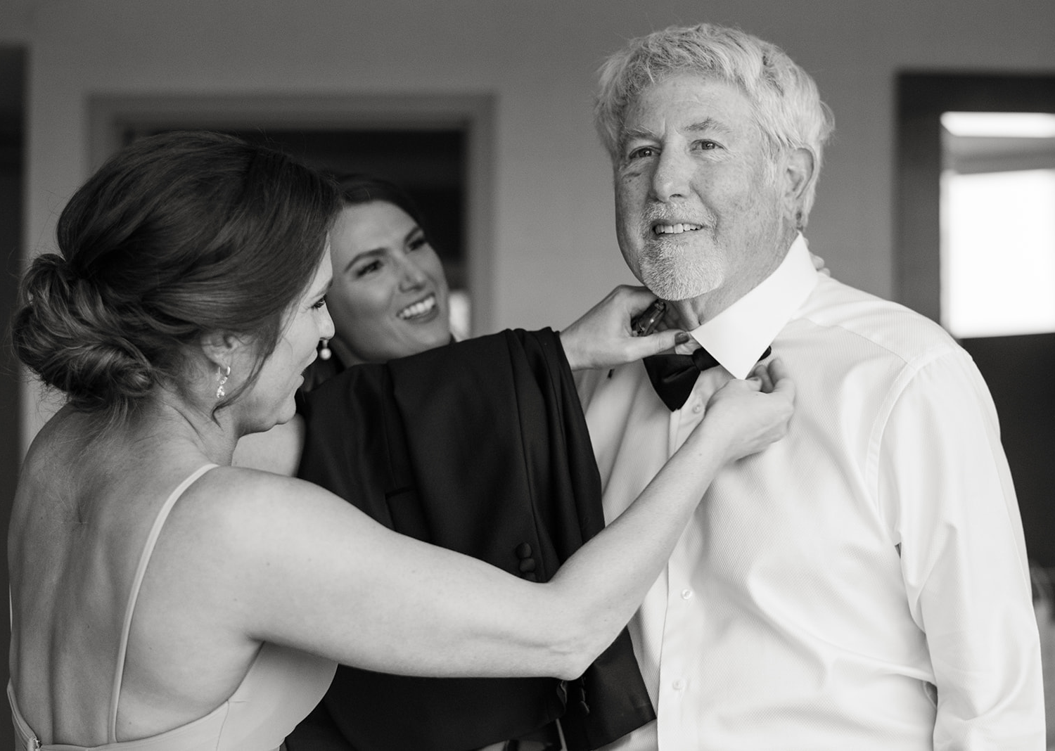 bridesmaid helping father of the bride put on his bow tie