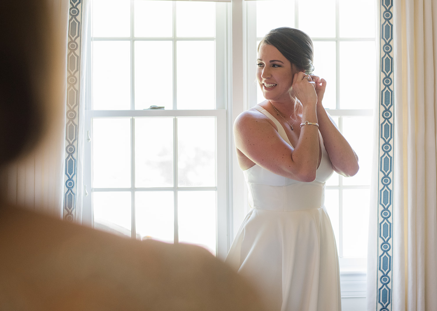 bride putting on her earrings as she puts on the last touches of her wedding day