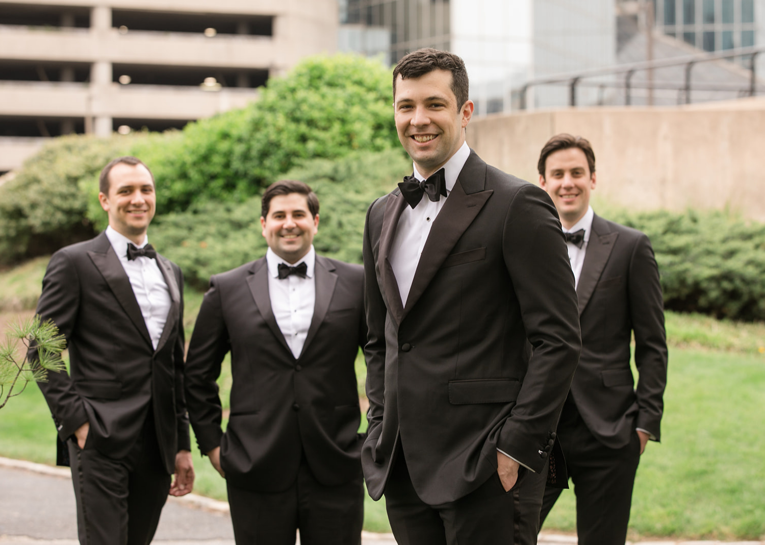 groom stands in front of the groomsmen as the groomsmen stand behind him smiling