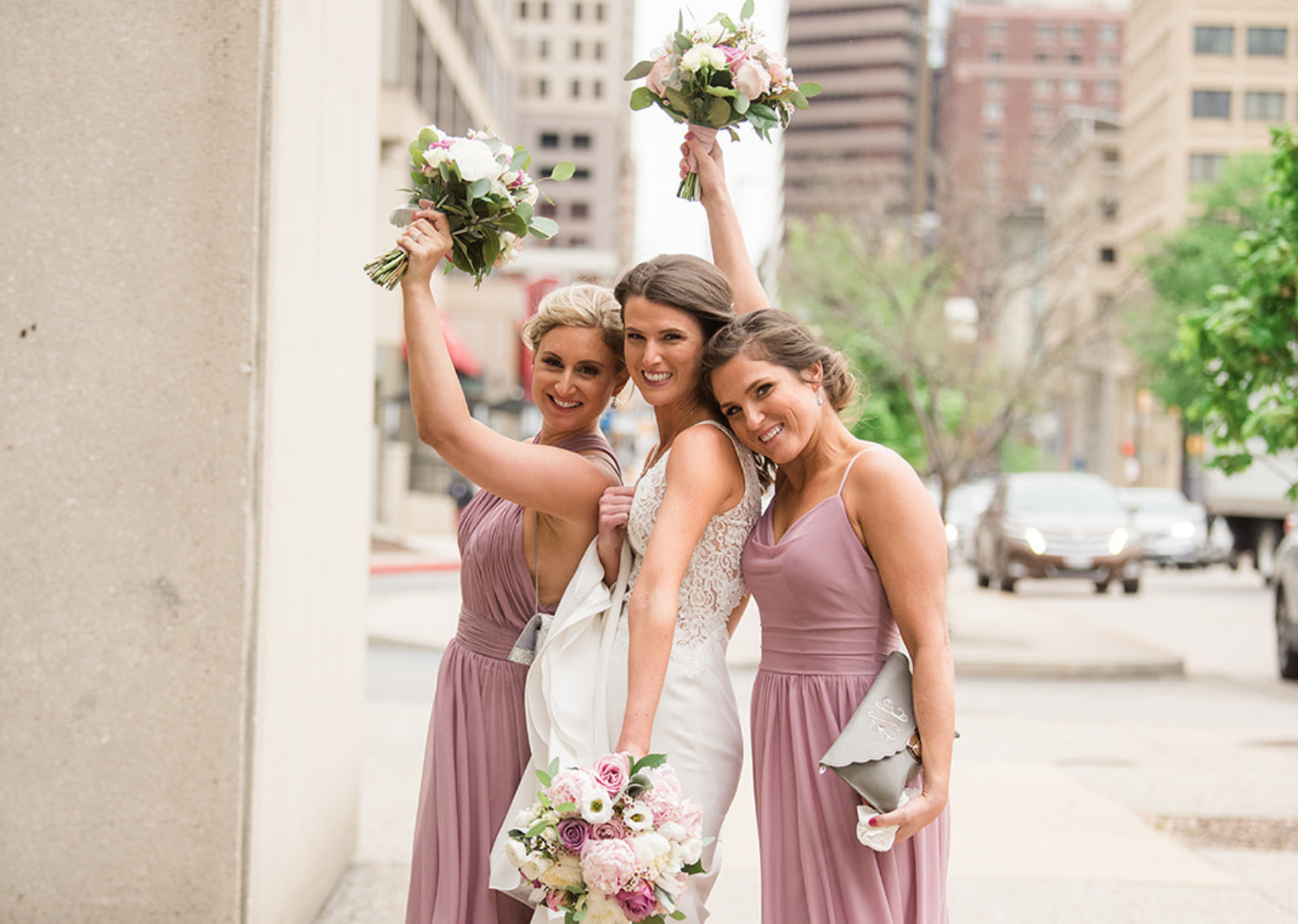 bridesmaids and bride holding their bouquet in the air smiling