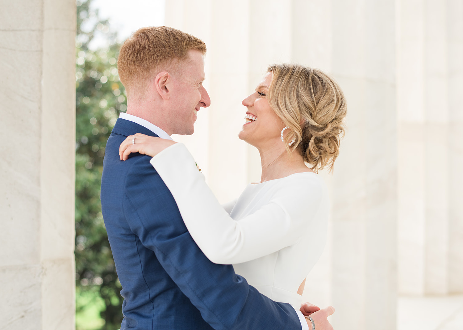 bride and groom smile as they look at eachother in the lincoln memorial