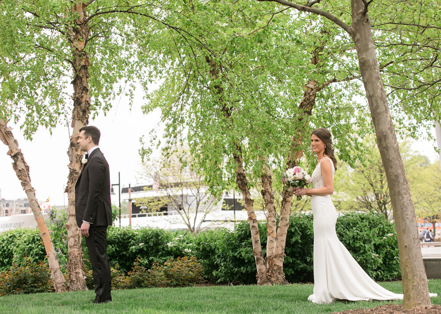 bride stands behind the groom as she approaches him for their first look