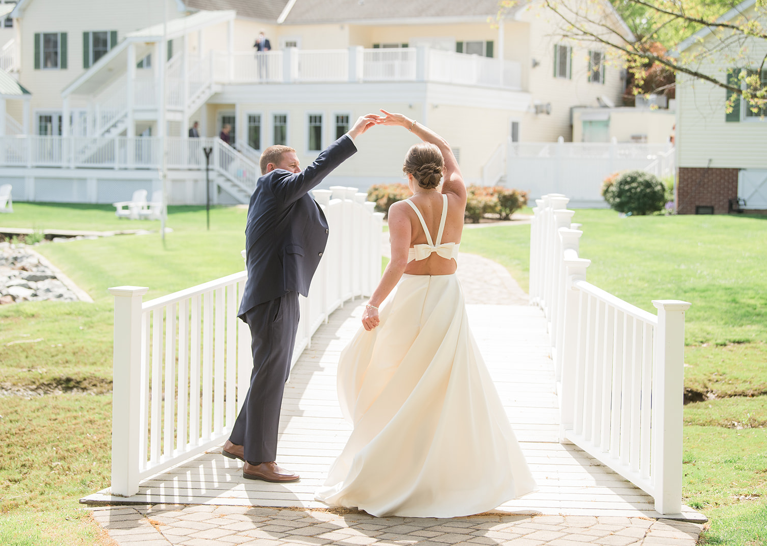 bride and groom standing in front of a bridge. the groom spins his bride