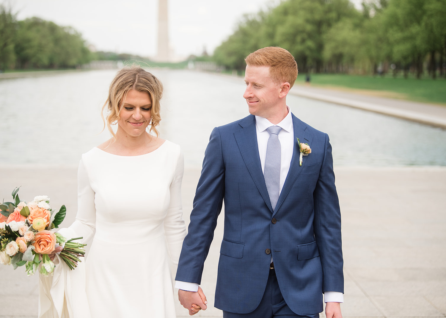 bride and groom smiling as they walk in front of the Washington Monument