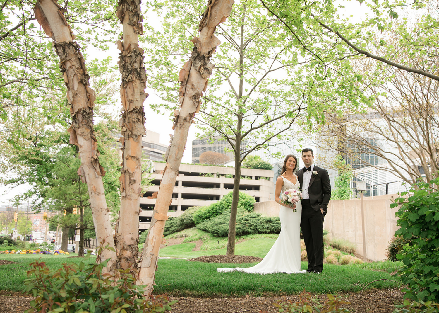 bride and groom smile as they stand in a park in Baltimore