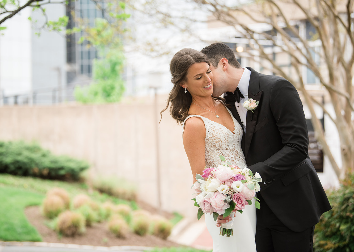 bride smiles as groom kisses her neck