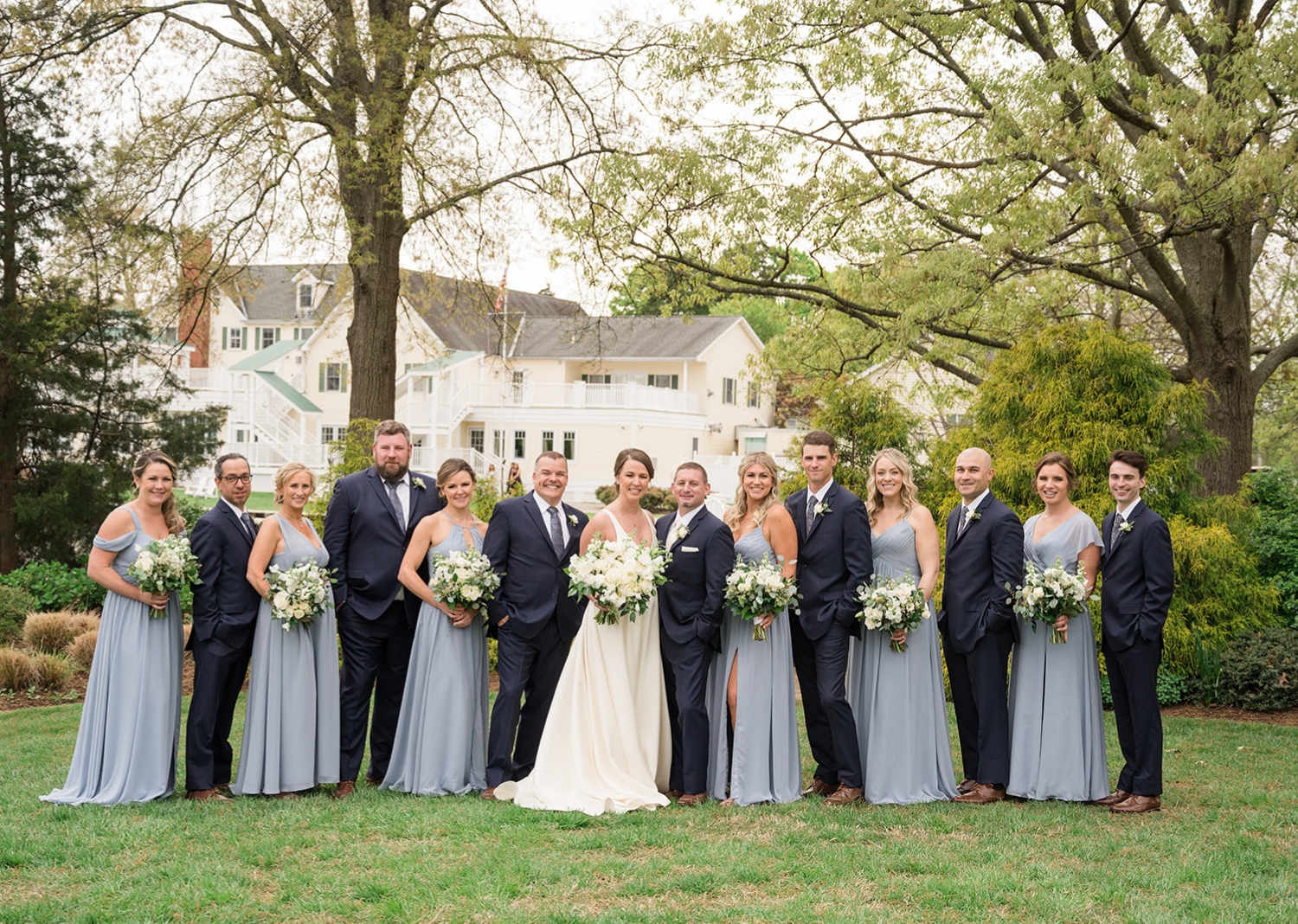 bride and groom smile surrounded by their wedding party