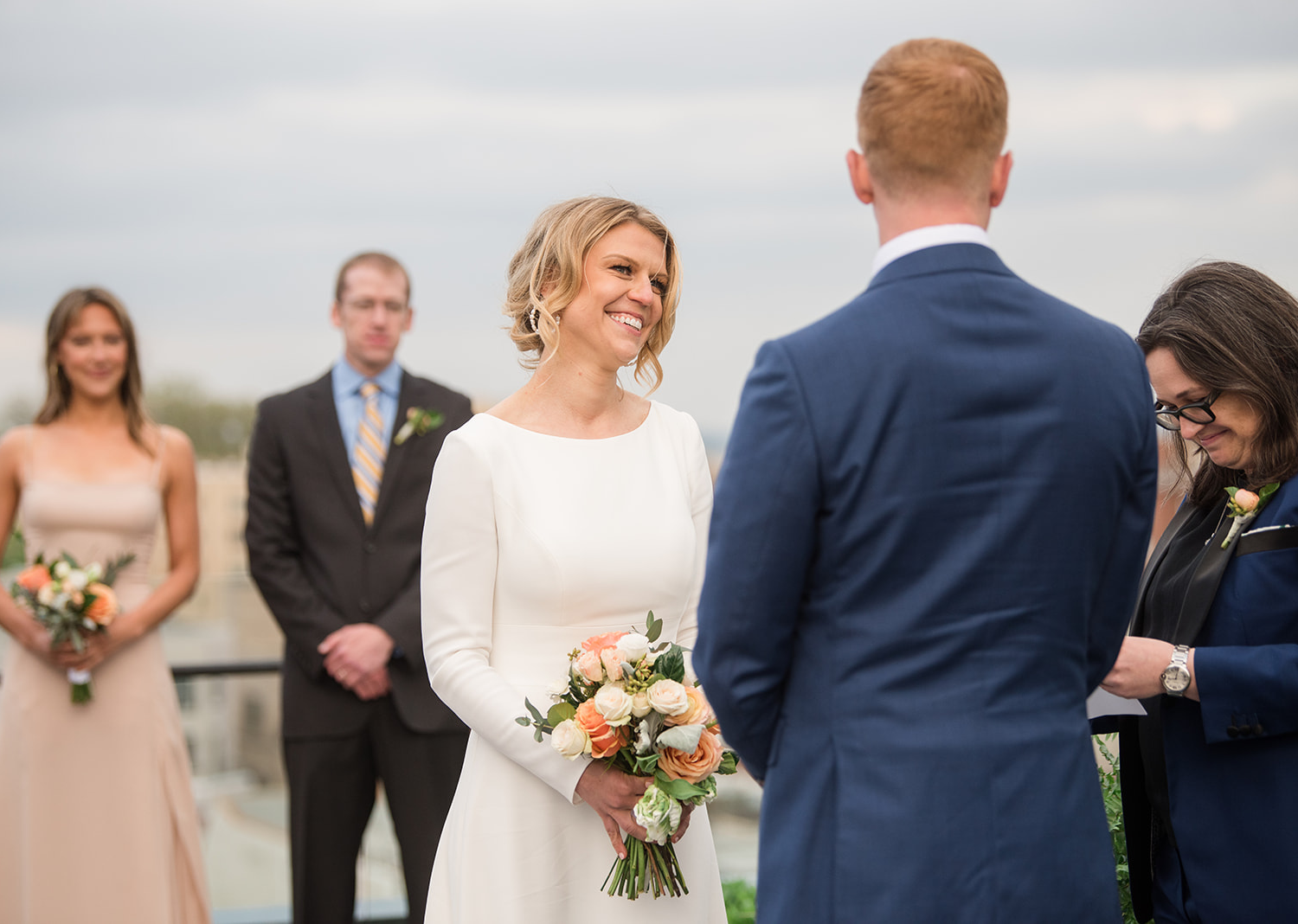 bride and groom smiling as they listen to their wedding talk on the rooftop of the line hotel in Washington