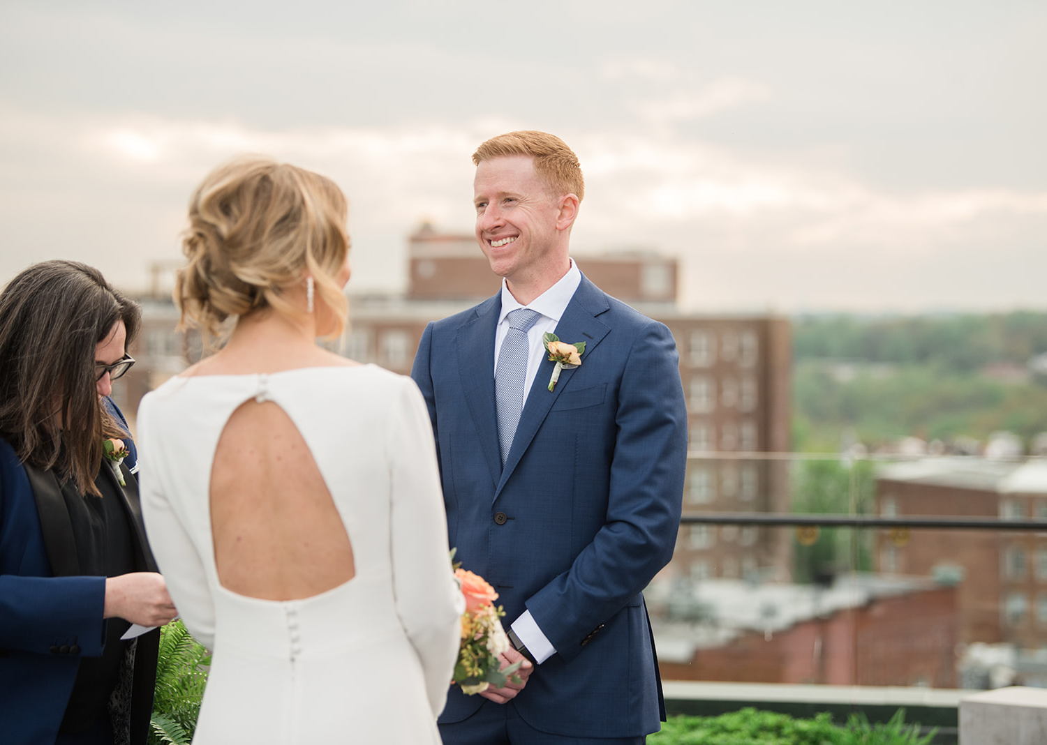 bride and groom smiling as they listen to their wedding talk on the rooftop of the line hotel in Washington