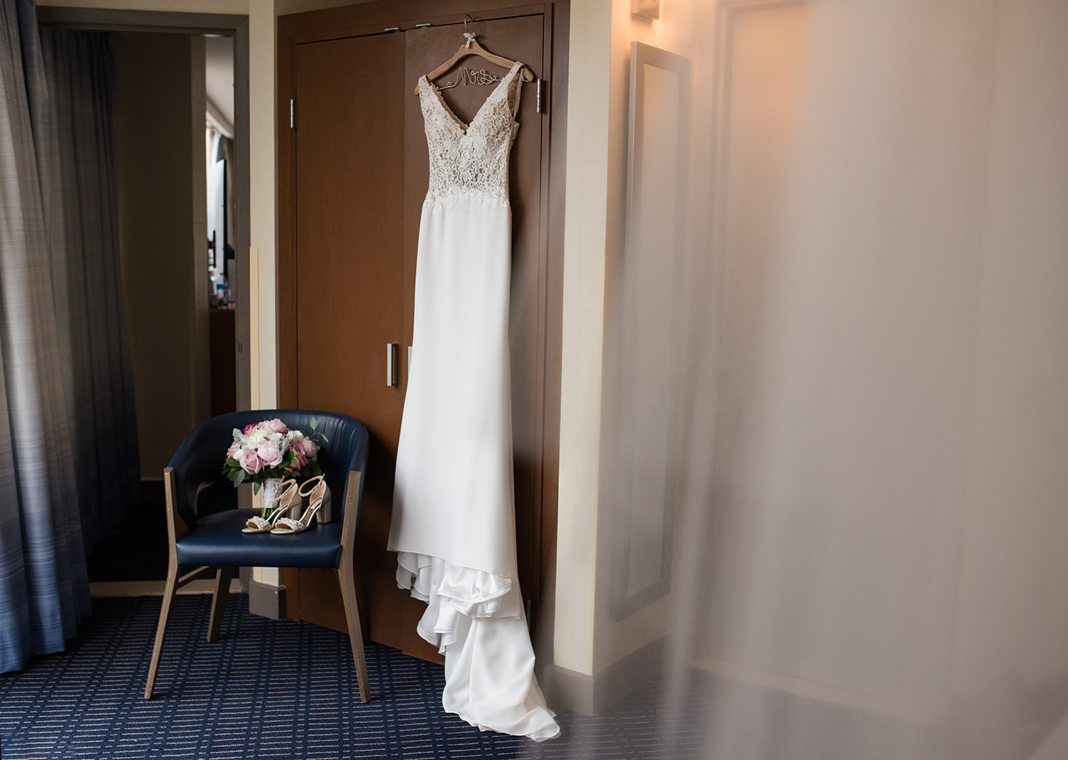 wedding dress hanging over door of bridal suite