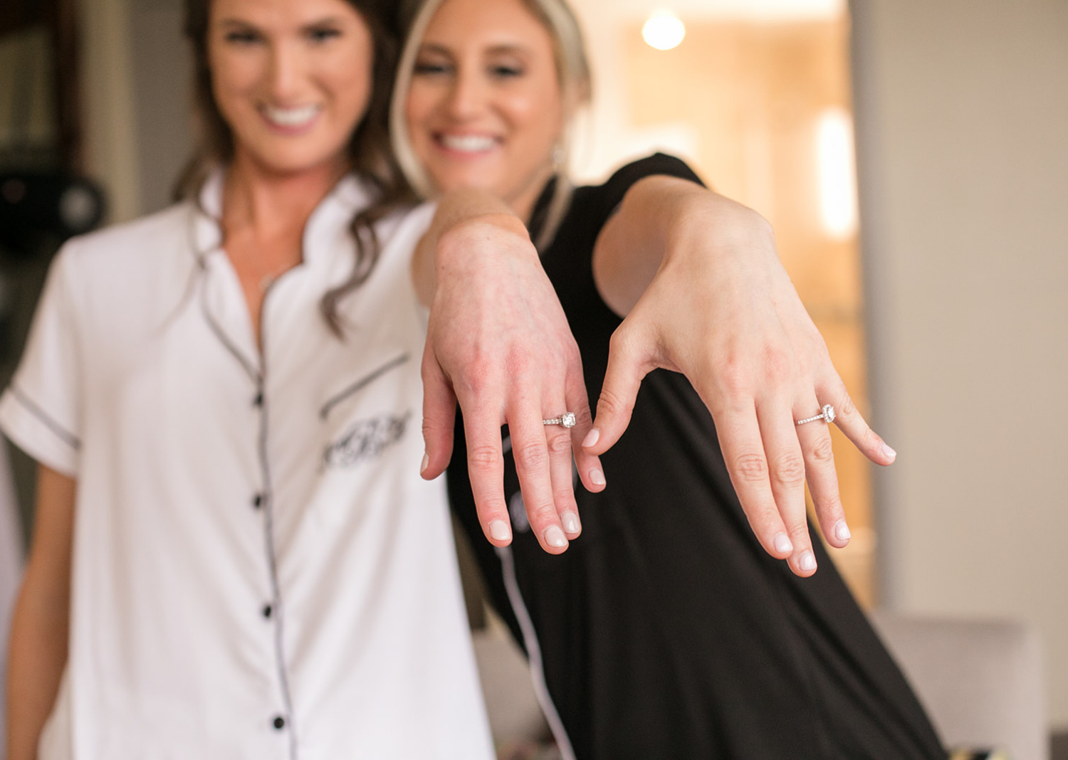 bride and bridesmaid showing off their engagement rings