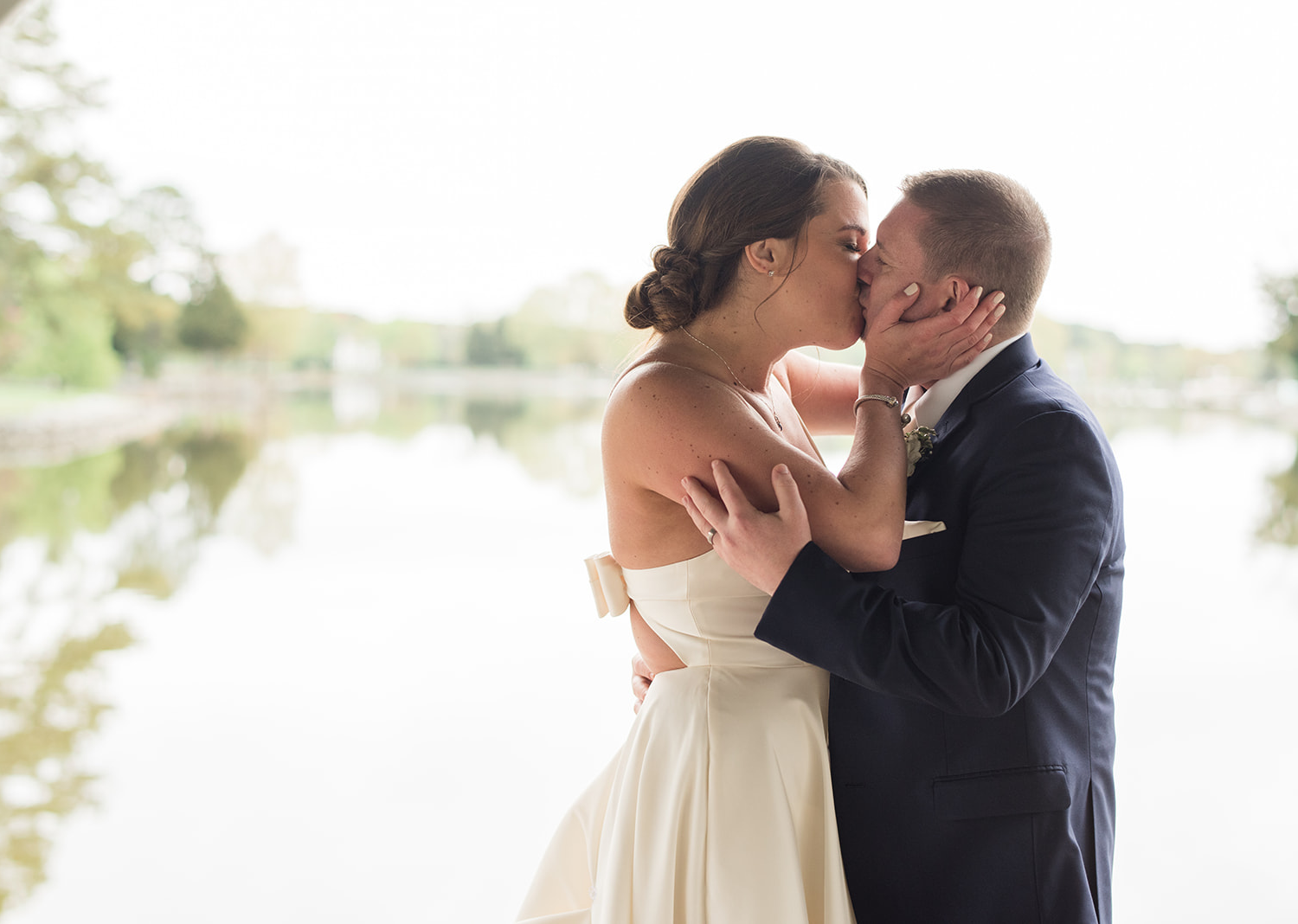 bride and groom share a kiss in front of the river