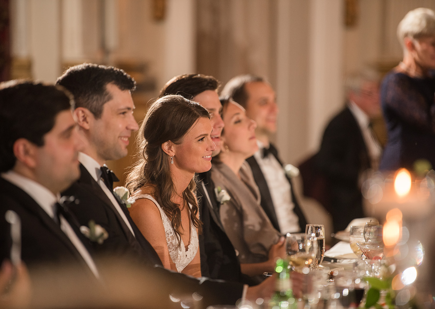 bride and groom smile as they hear speeches from their friends and family