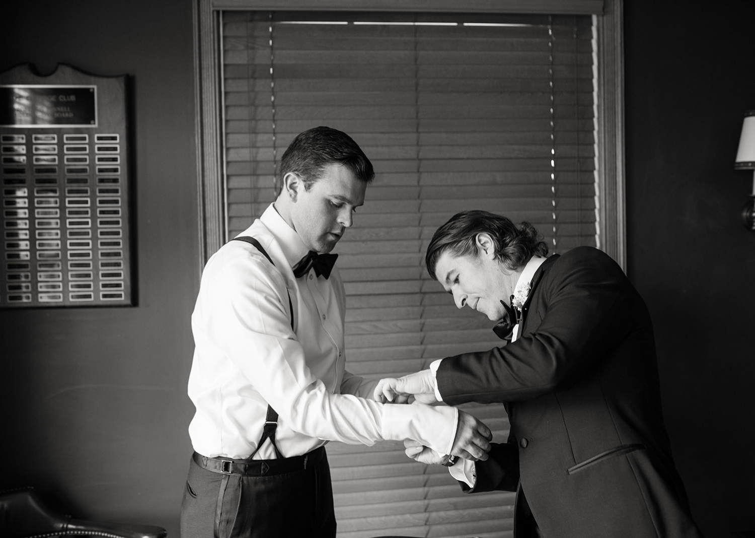 groomsmen helping the groom with his cufflinks 