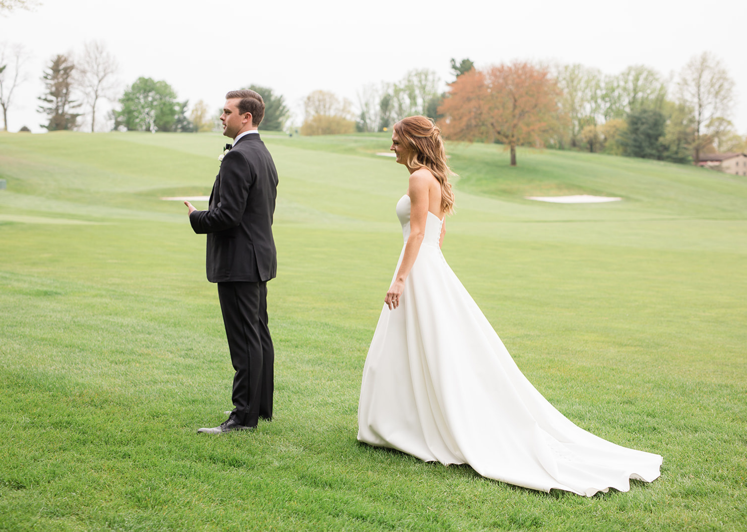 bride standing behind the groom getting ready for their first look