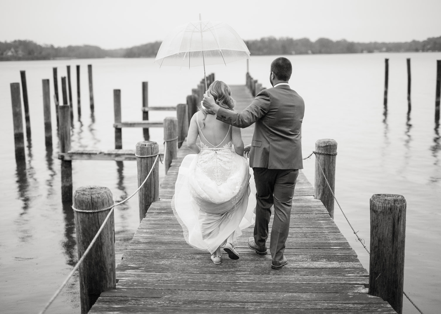 black and white portrait of the bride and groom holding the umbrella as it rains