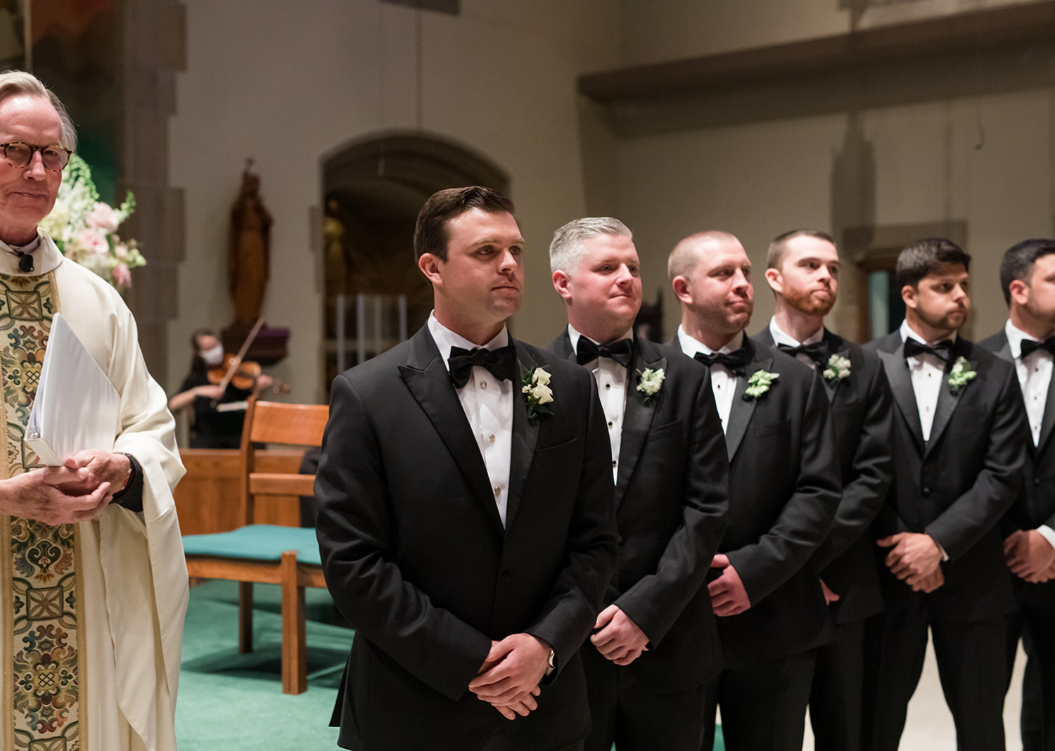 groom standing with his groomsmen waiting at the end of the aisle for his bride 