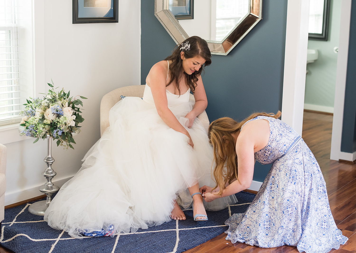 bridesmaid helping the bride put on her shoes 