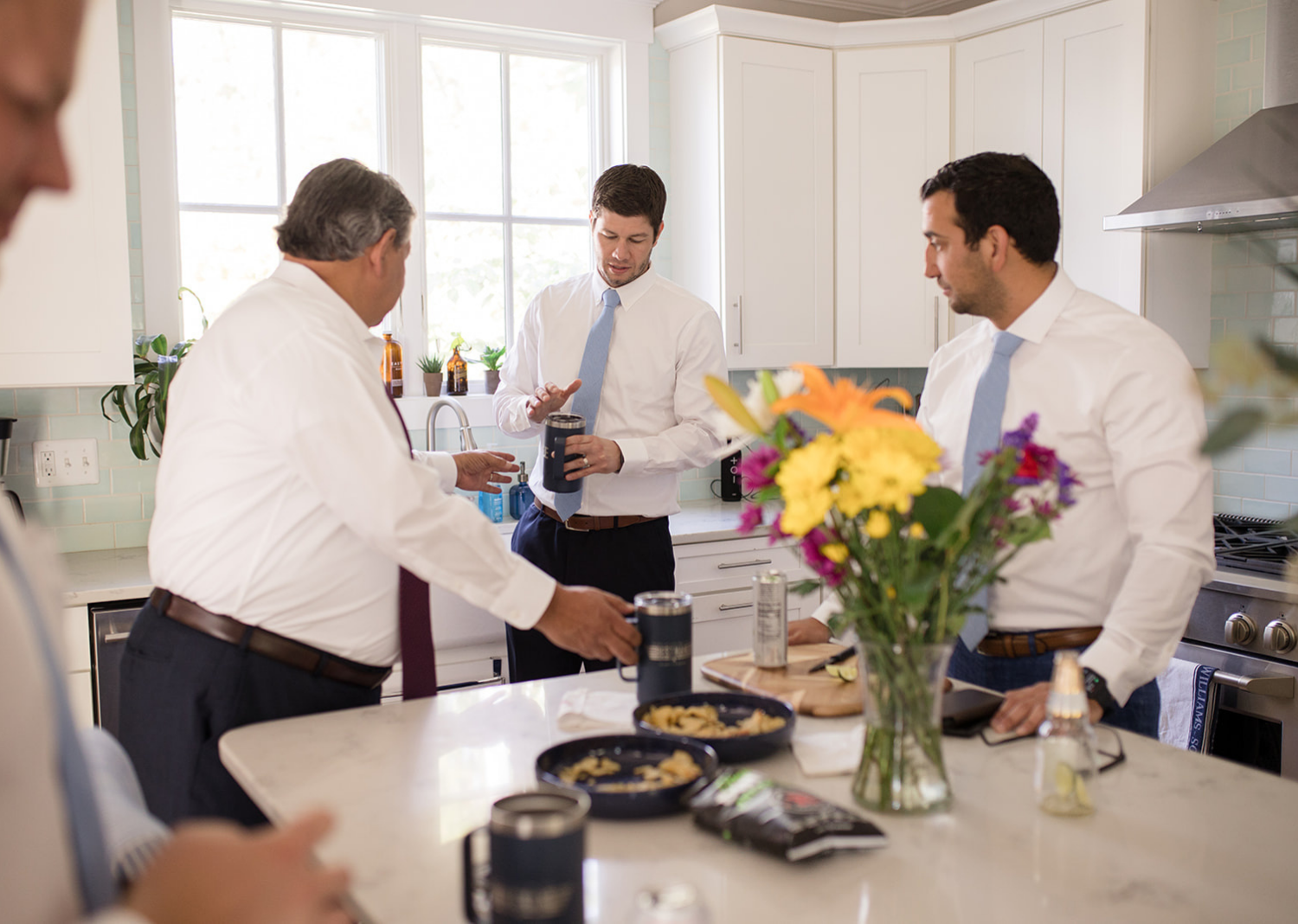 groom and groomsmen sharing a drink in the kitchen area before the wedding day