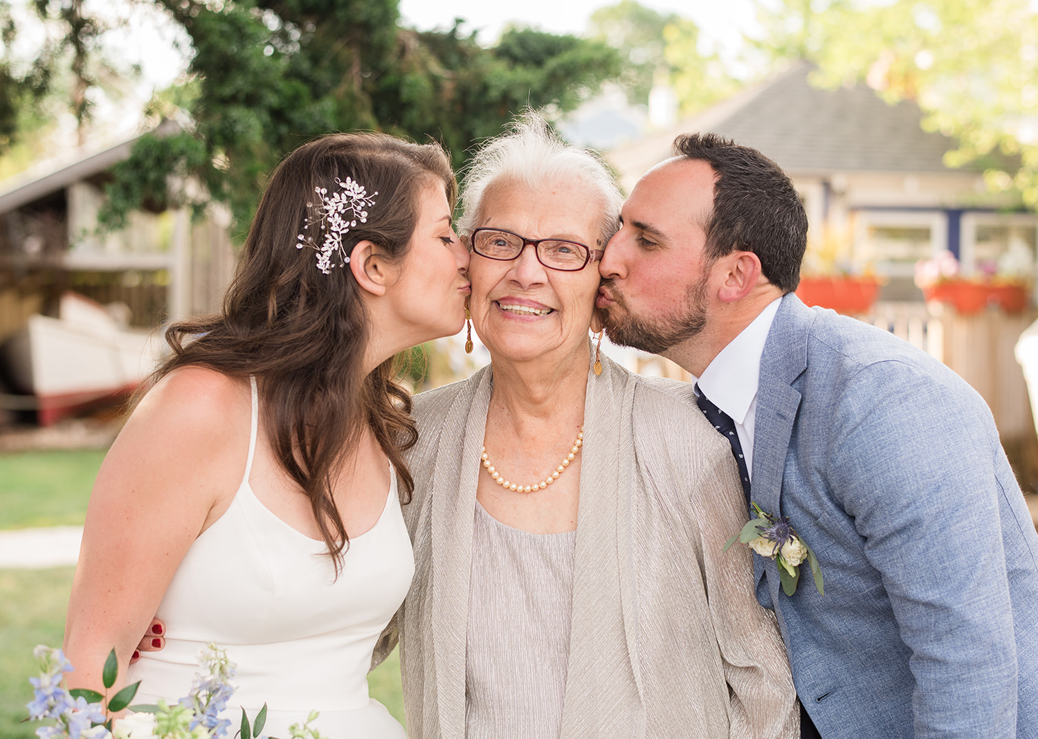 bride and groom both kiss grandma on the cheeks