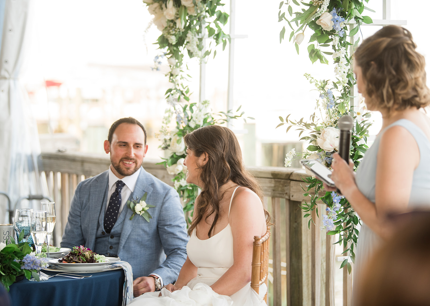 bride and groom smile at eachother as they hear the bridesmaid wedding speech