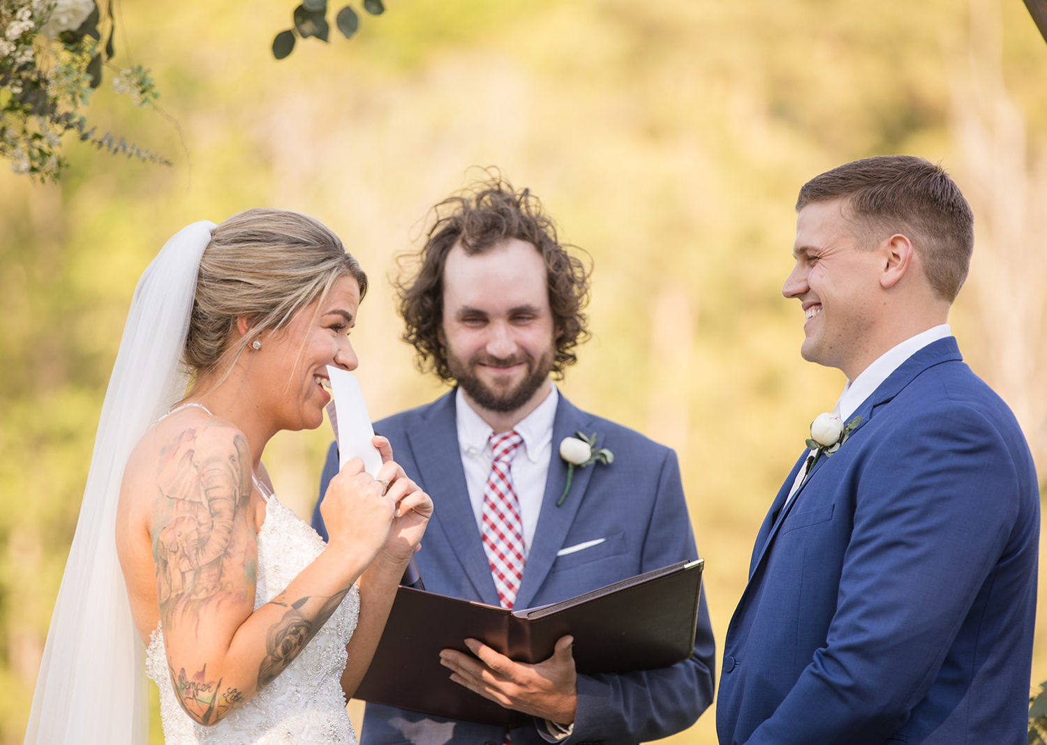 bride smiles as she reads wedding vows to the groom