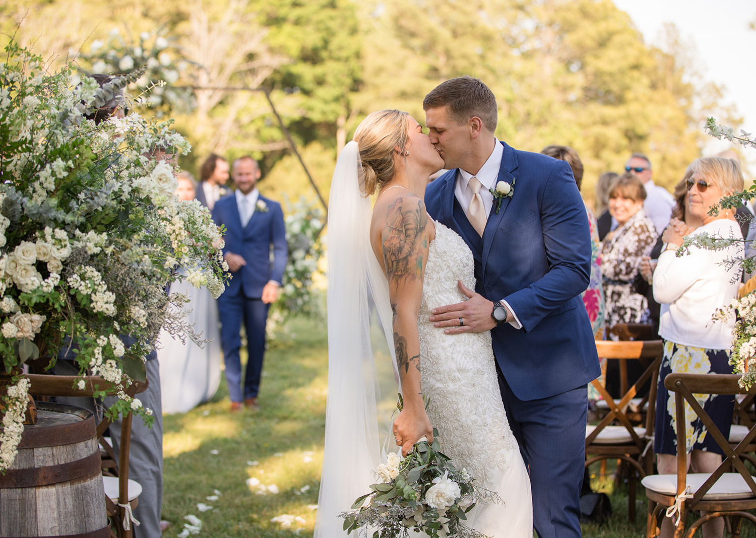 groom kisses bride as they walk down the aisle 