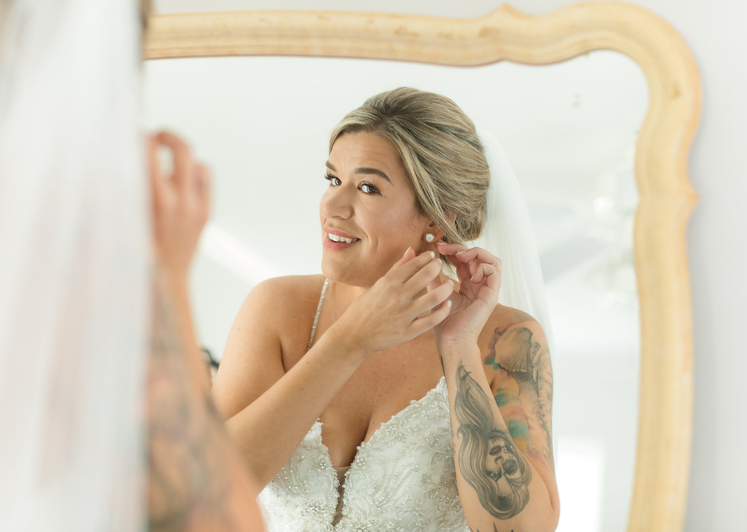 bride looking at herself in the mirror while putting on her earrings