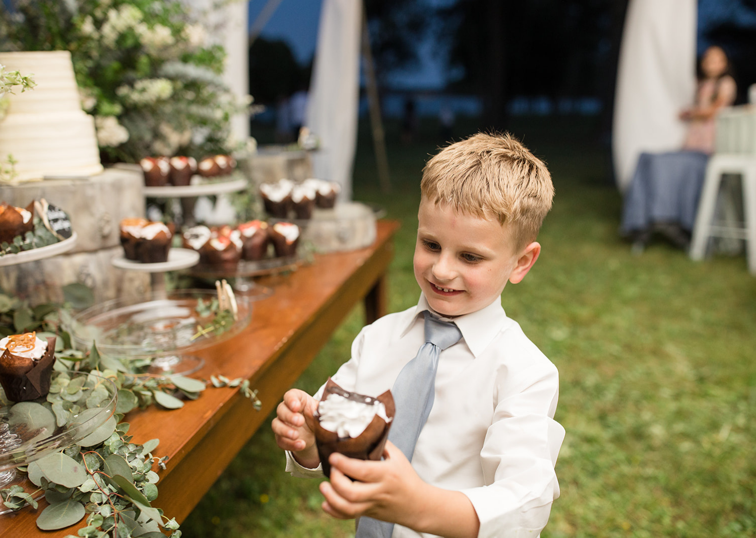 little groomsmen eating a cupcake from the dessert table 