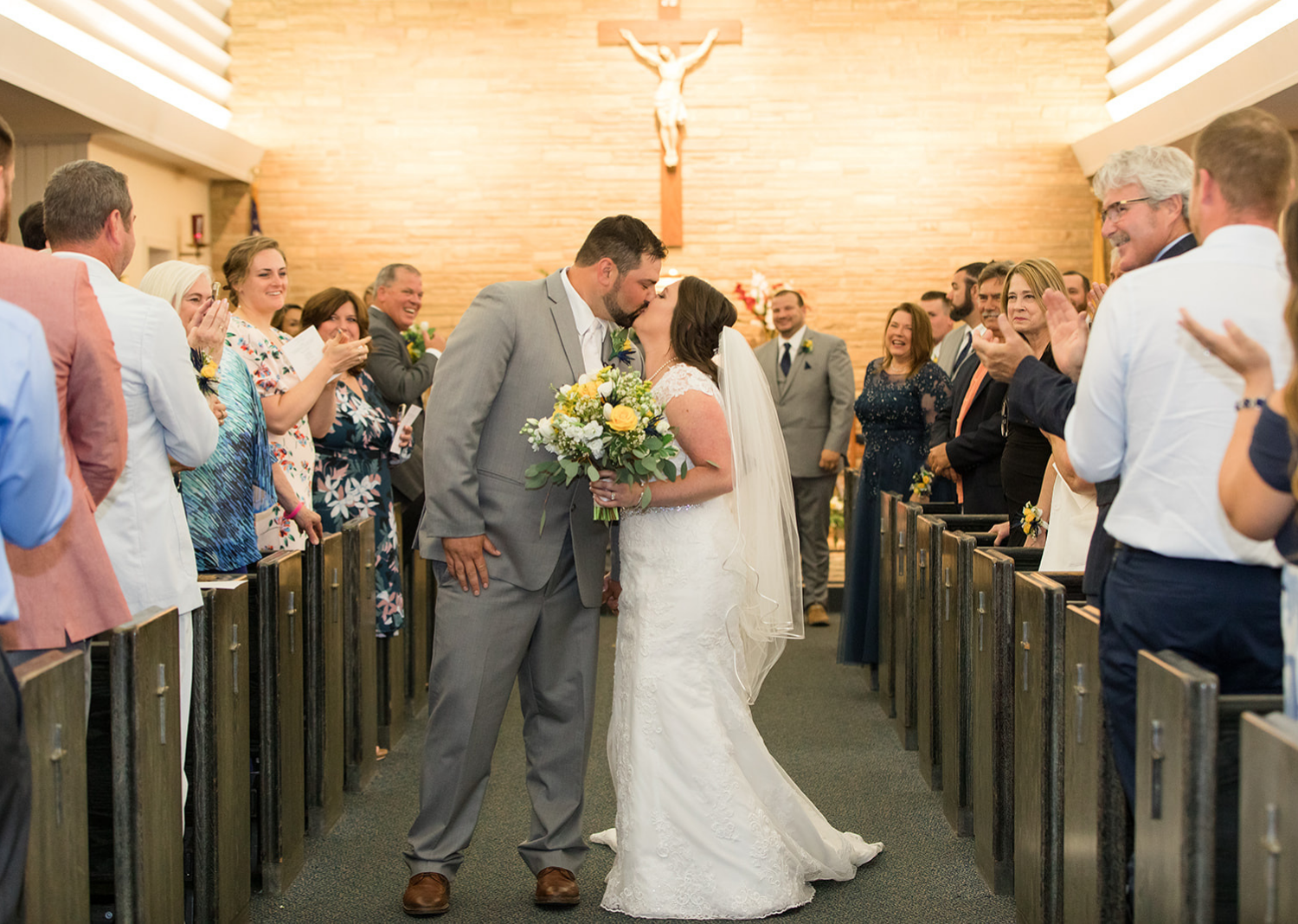 bride and groom share a kiss while walking down the aisle