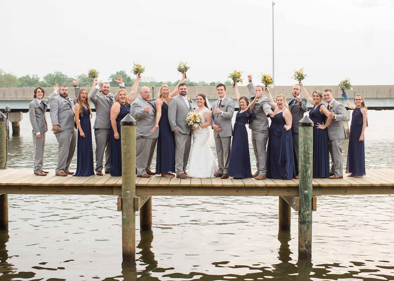 bride and groom with their wedding party on the pier 