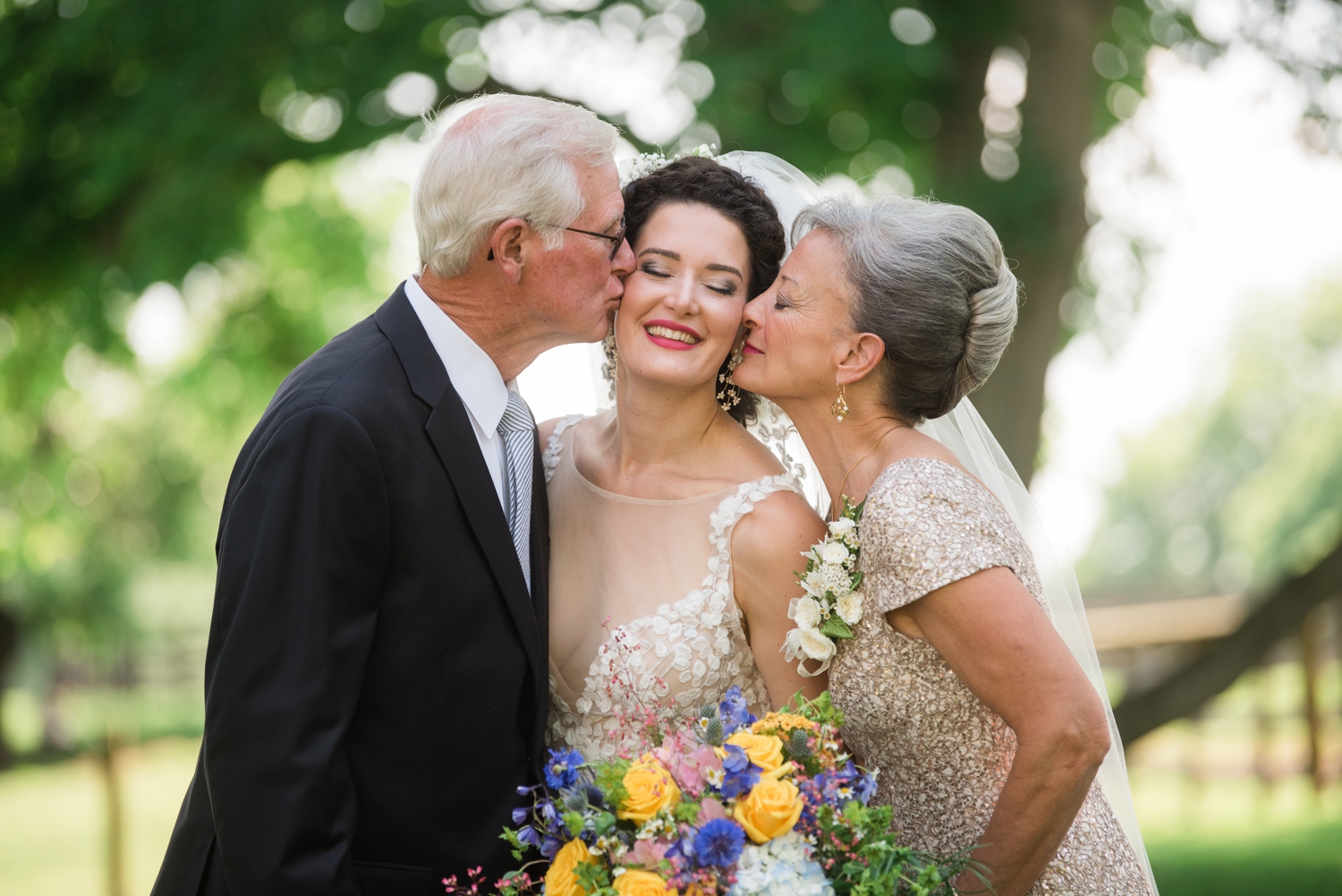 brides parents kiss her on the cheek