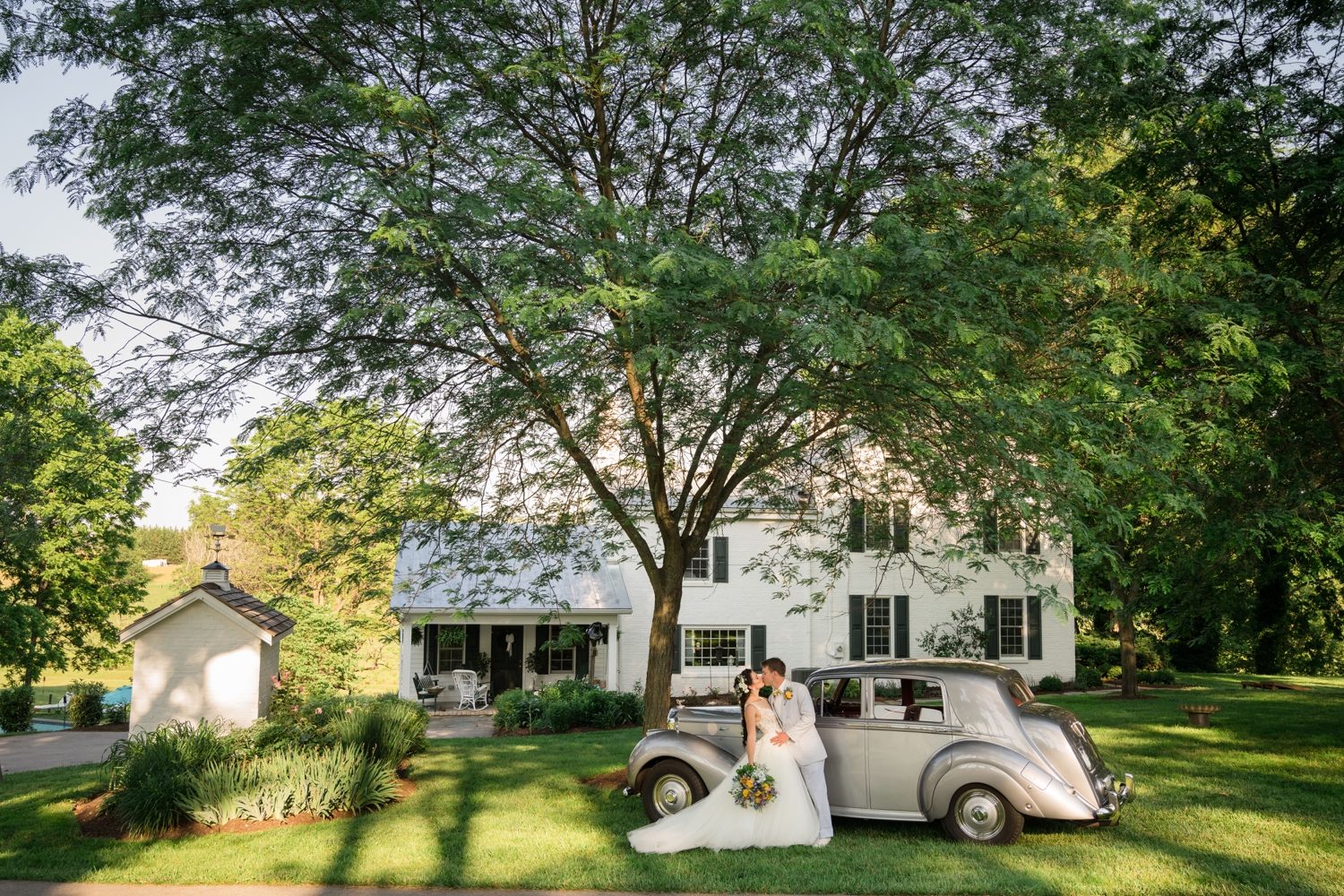 bride and groom kiss by a vintage car