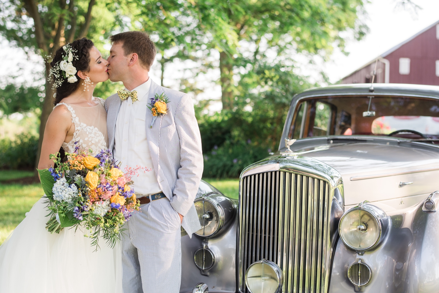 bride and groom kiss by a vintage car