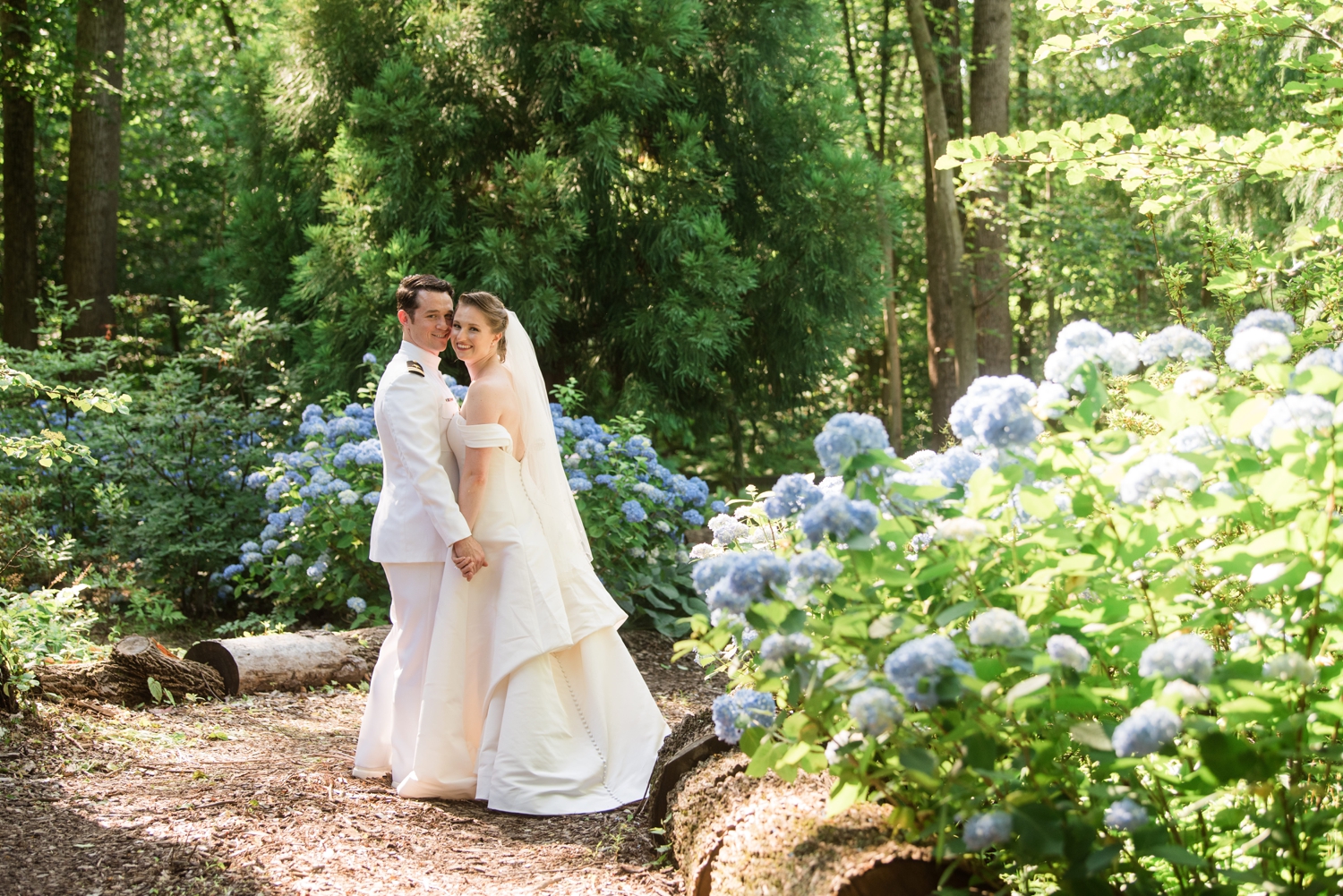 bride and groom pose cheek-to-cheek by a blue hydrangea bush